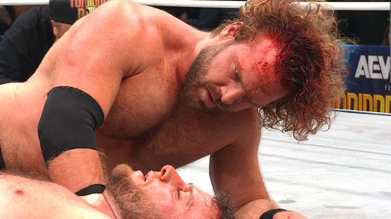 Hangman Adam Page looking at a defeated MJF