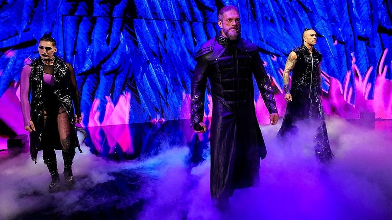 Rhea Ripley, Edge [Adam Copeland], and Damian Priest as The Judgment Day on their way to the ring.