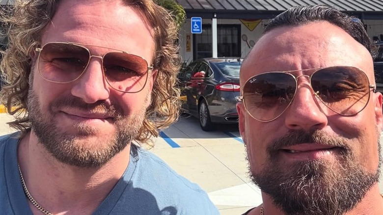 'Hangman' Adam Page posing alongside Marty Scurll outside of a Cracker Barrel Old Country Store.