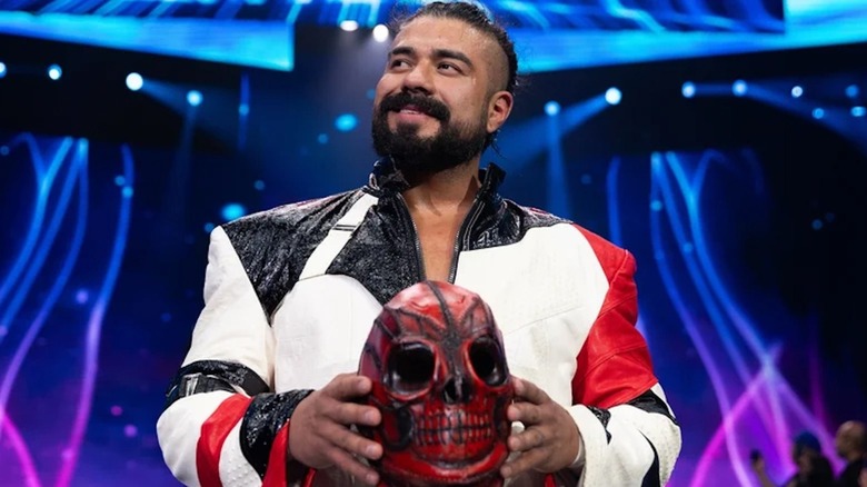 Andrade El Idolo smiling with his red mask ahead of his entrance to the ring during an AEW show.