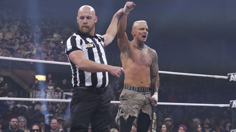 A referee holds up the arm of AEW World Champion Darby Allin after a successful victory on 