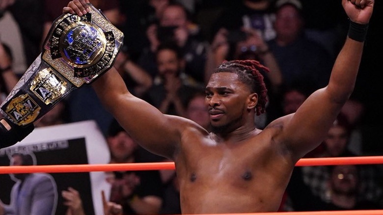 One-half of Private Party, Marq Quen, holds up the AEW World Tag Team Championship after a successful defense
