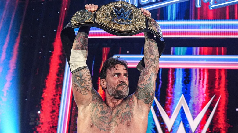 CM Punk holding the World Heavyweight Championship above his head after winning the title.