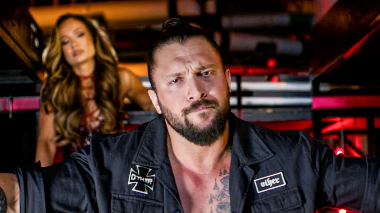 Karrion Kross backstage - with Scarlett Bordeaux in the background - during a promo segment.