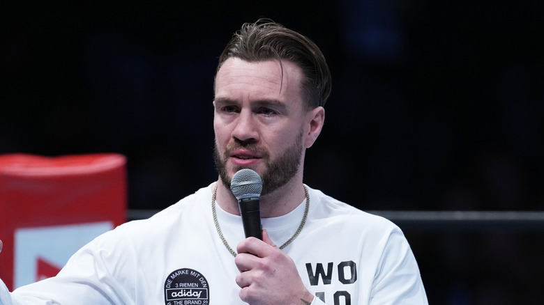 Will Ospreay holding a microphone