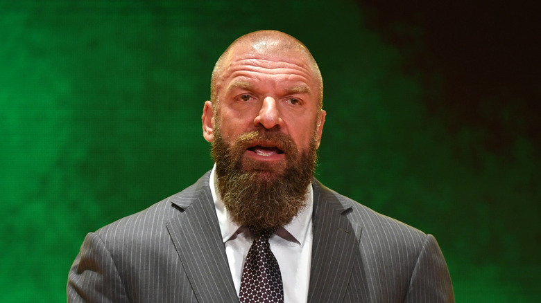 Triple H standing in front of a giant green background