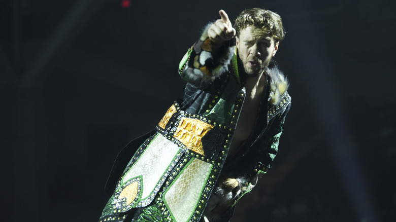 Will Ospreay poses on the ropes and points to the crowd before a match on 