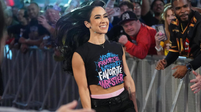AJ lee smiles as she skips down the entrance ramp.