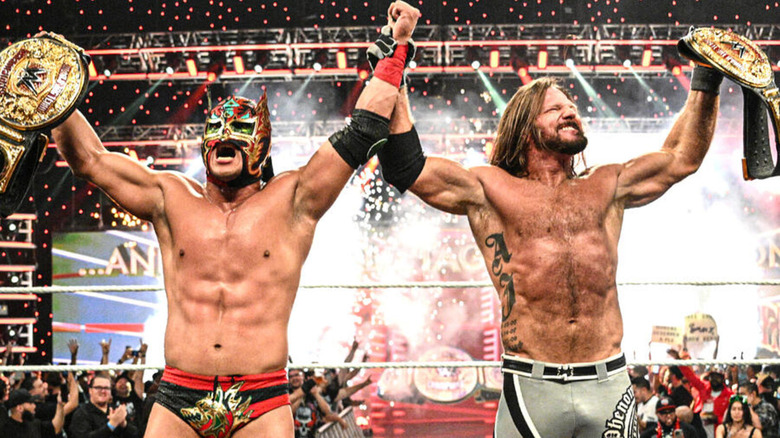 Dragon Lee and AJ Styles hold hands in celebration as they show off their newly-won WWE World Tag Team Championships.