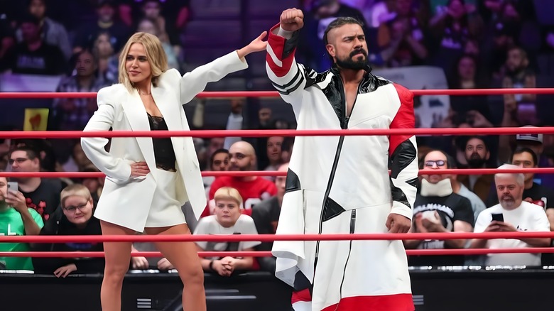 CJ Perry raises the hand of her new client, Andrade El Idolo