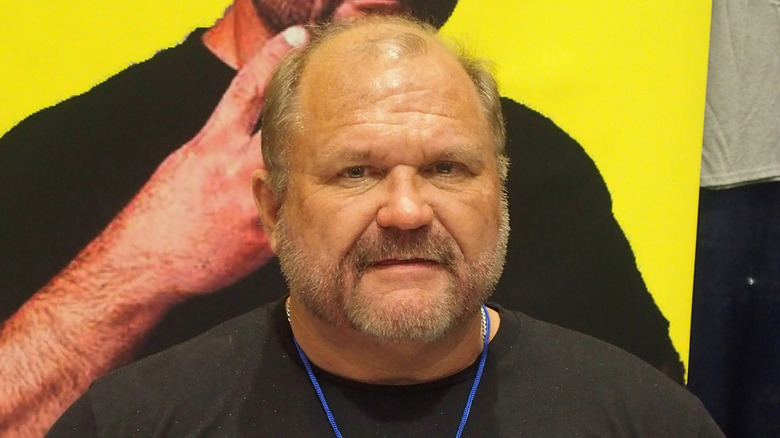 Arn Anderson standing in front of a poster of himself
