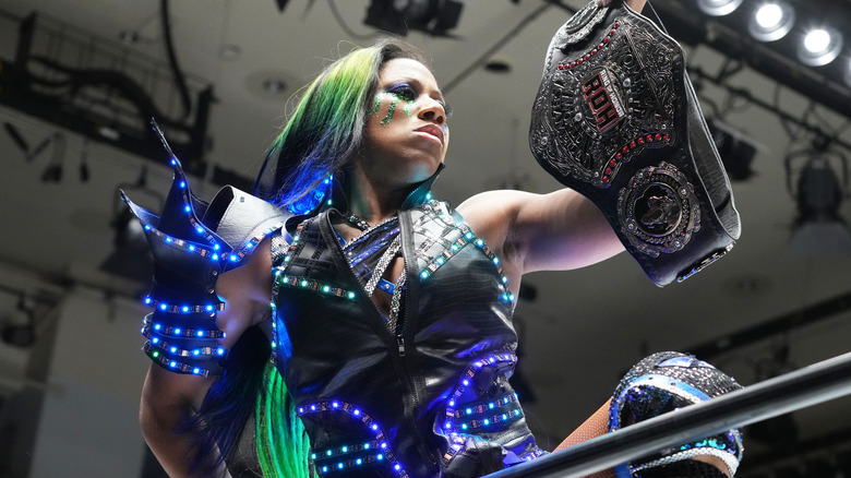 Athena holds up her Ring of Honor Women's World Championship as she mounts the rope during her entrance.