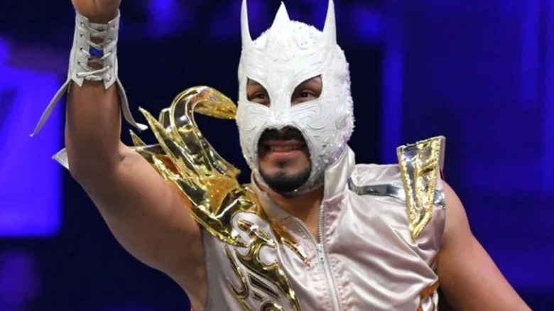 AEW star Komander poses and waves to the crowds on the ropes before a match on an episode of AEW programming.