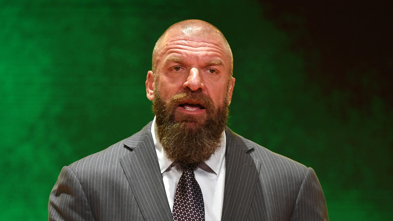 Triple H standing in front of a green background