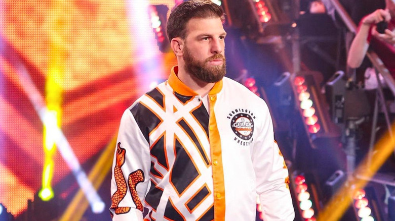 Drew Gulak wearing a white and orange bomber jacket