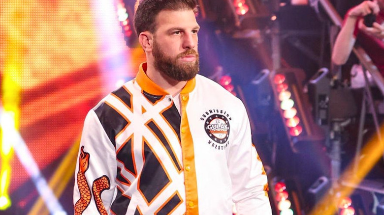 Drew Gulak wearing a white and orange bomber jacket