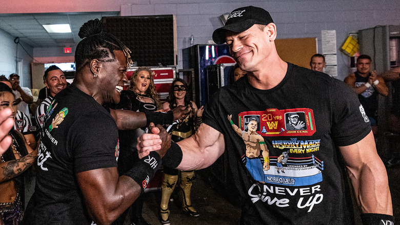 R-Truth shakes hands with John Cena as the locker room applauds both of them.