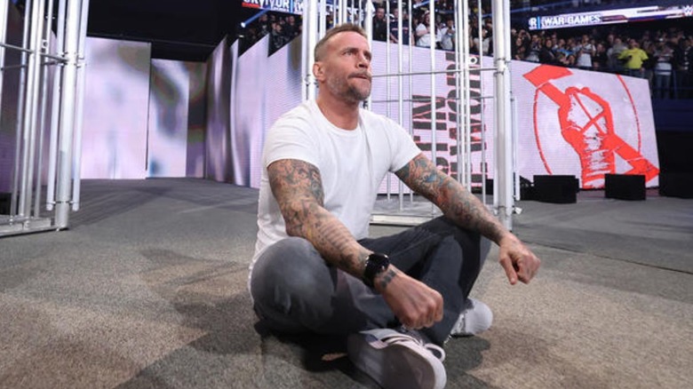 CM Punk sits on the stage at WWE Survivor Series: War Games.