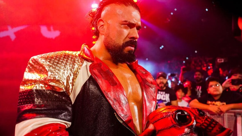 Andrade heads to the ring before a match, mask in hand, on WWE programming.