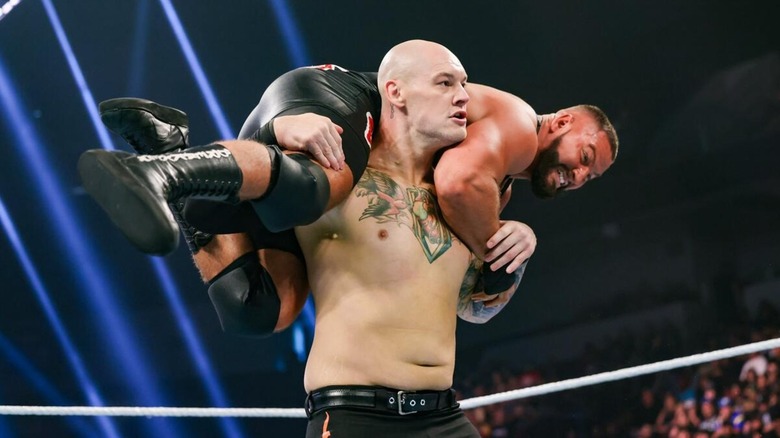 Baron Corbin holding Bron Breakker on his back