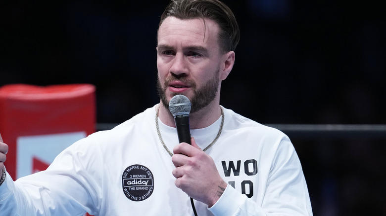 Will Ospreay holding a microphone