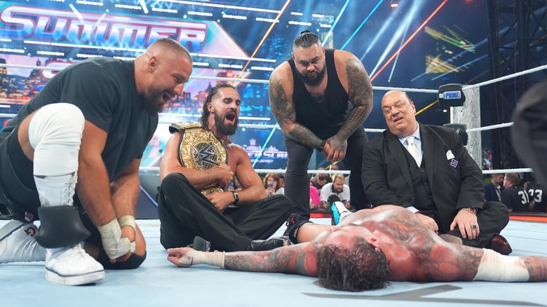 Seth Rollins with the World Heavyweight Championship and The Vision towering over an unconscious CM Punk shortly after his return at SummerSlam 2025 after faking an injury,
