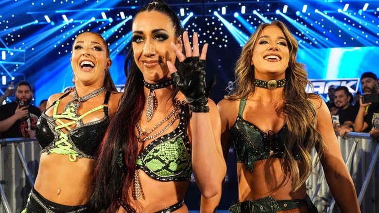 Jacy Jayne waves toward the ring, flanked by Fatal Influence stablemates Fallon Henley and Lainey Reid, during their "WWE SmackDown" debut.
