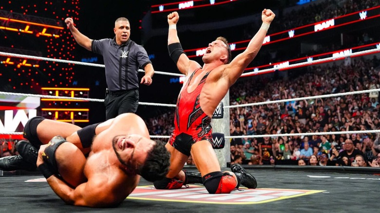Chad Gable poses in victory, as a referee is position behind him, Ethan Page, clutching his ankle in the foreground, after winning a gauntlet match on "WWE Raw" to become number one contender for Penta's Intercontinental Championship.