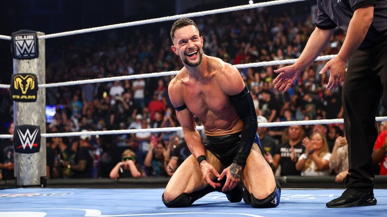 Finn Balor kneels in the ring and smiles following a four-way victory to determine a challenger for Sami Zayn and the number one contendership at WWE SummerSlam on "WWE SmackDown."