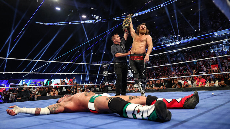 Sami Zayn holds up the WWE Title.
