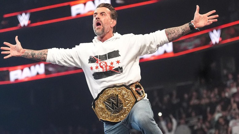 CM Punk stands on the ropes and poses for the fans ahead of a segment with Roman Reigns on "WWE Raw."