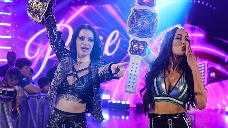 Paige and Nikki Bella pose with the WWE Women's World Tag Team Championships as they make their way down the ramp to the ring for a match on 