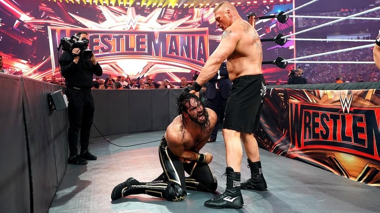 Brock Lesnar grabs Seth Rollins by the hair and shoulder outside of the ring during their WrestleMania 35 match.