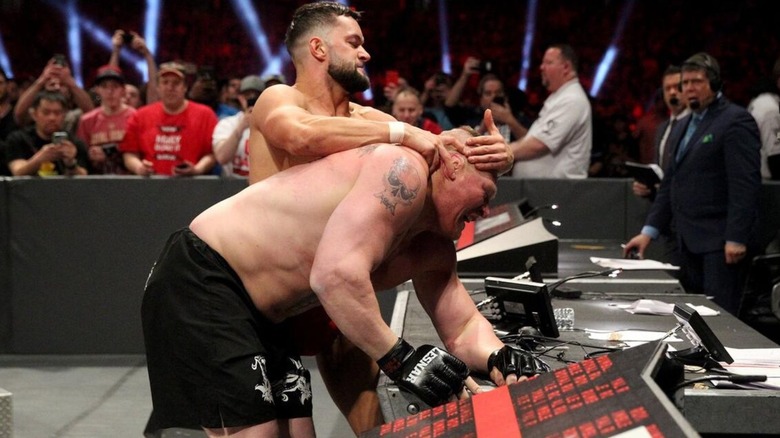 Finn Balor looks to hit Brock Lesnar's head off the commentary desk during their match at the Royal Rumble.
