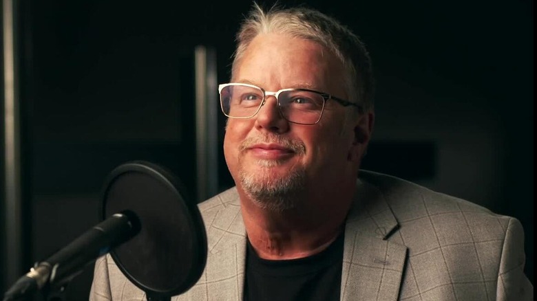 Bruce Prichard poses in front of an in-studio microphone