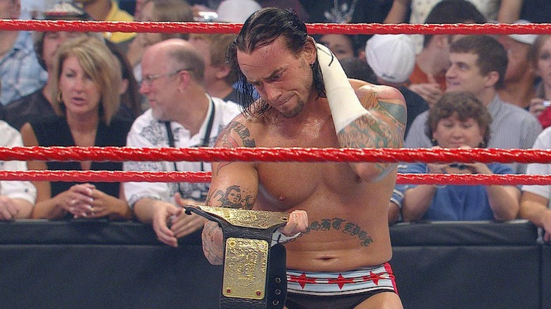 CM Punk stares at a championship title belt