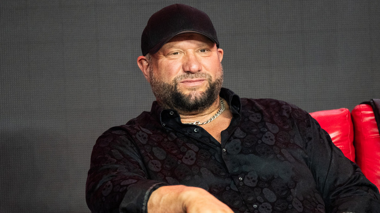 Bully Ray in a black shirt and cap sitting on a red couch