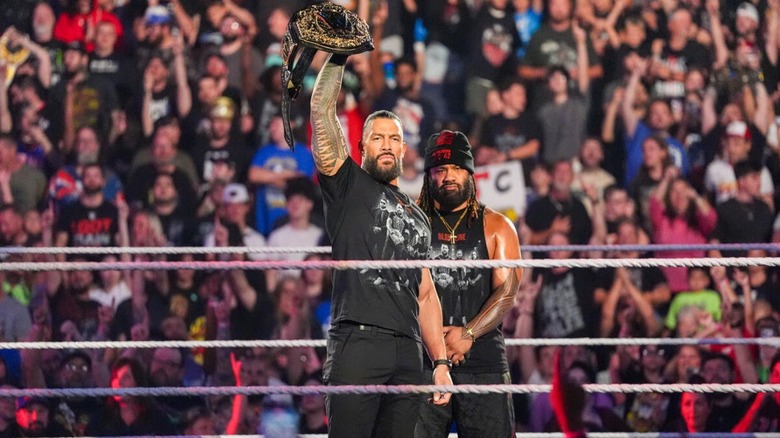 World Heavyweight Champion Roman Reigns holds his title aloft, as Jacob Fatu stands behind him, as he makes his entrance during the August 17, 2026 edition of "WWE Raw."