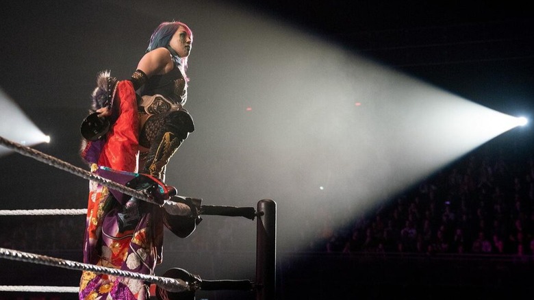 With a single spotlight shining on her, Asuka looks out into the crowd during a WWE event