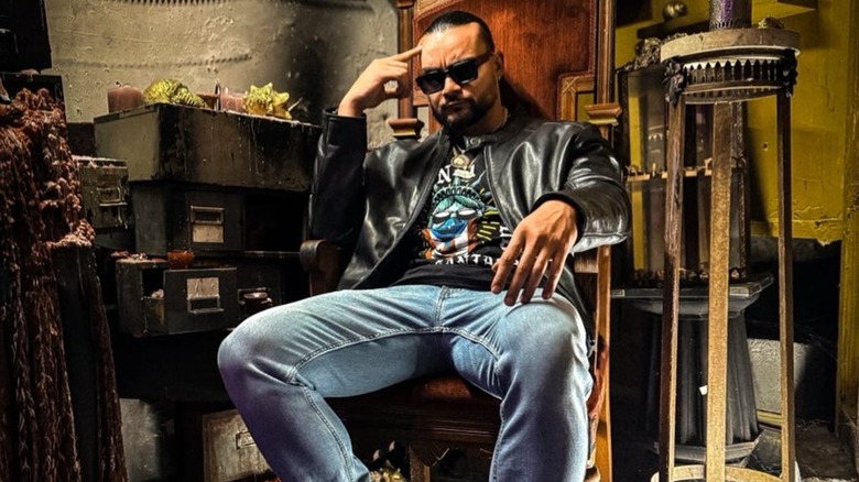 Mike Santana sitting on a chair, posing for a photoshoot.