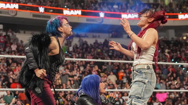 Asuka hits IYO SKY with the blue mist while Kairi Sane ducks in the middle of the ring during their confrontation on 