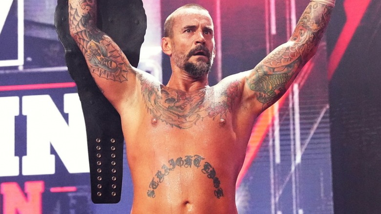 CM Punk raises his arms and title belt