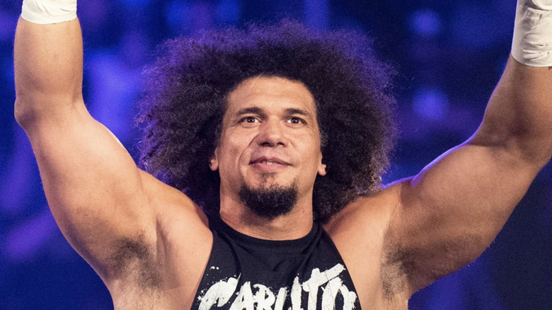 Carlito holds his hands up during his entrance.