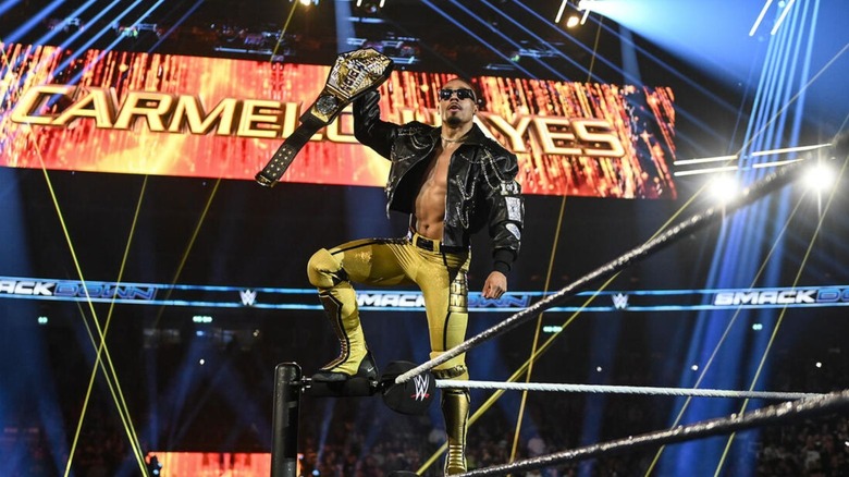 Carmelo Hayes raises the United States Championship as he stands on the ropes before a match on 