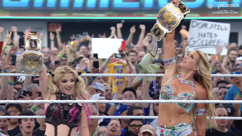 Alexa Bliss and Charlotte Flair raise the WWE Women's Tag Team Championships.