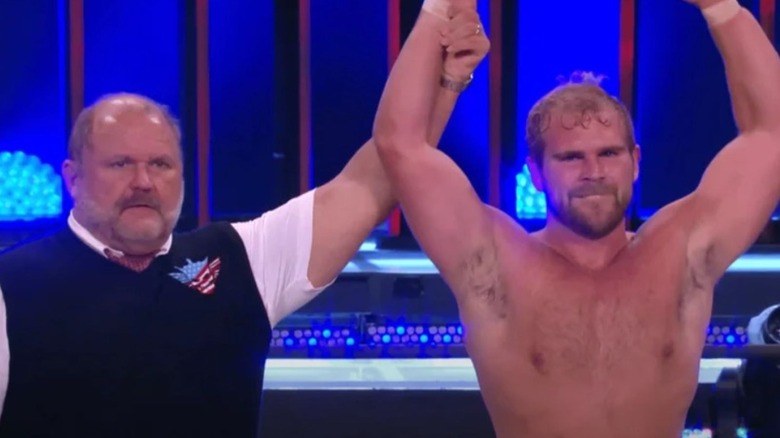 Arn Anderson holds up the arm of his son, Brock, on the stage during an episode of AEW programming.