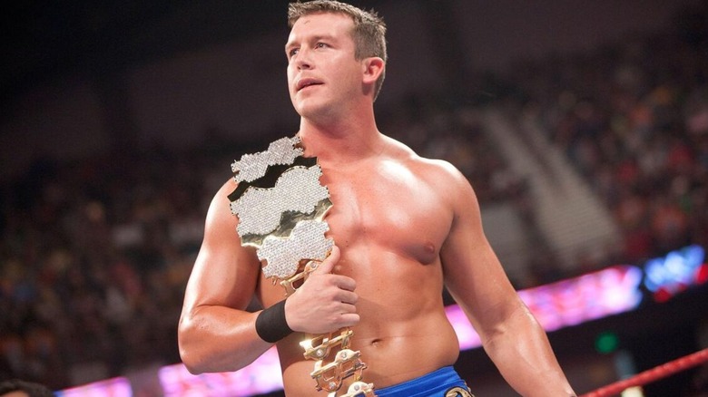Ted DiBiase Jr. looks to the crowd during a WWE taping, the Million Dollar Championship across his shoulder.
