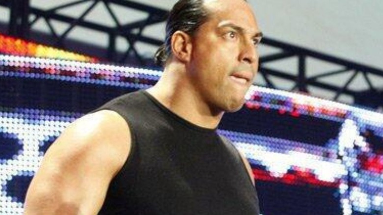 Sim Snuka stands beside Manu as he cuts a promo on the stage during an episode of WWE programming.