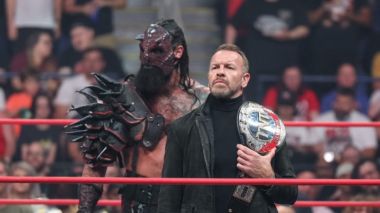 Christian Cage stands beside Luchasaurus