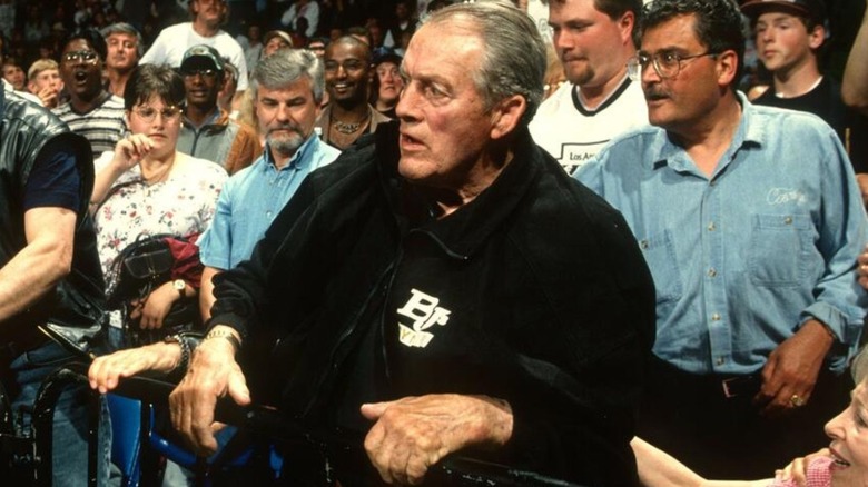 Stu Hart is seen standing the crowd at the ring barricade during a WWF show.